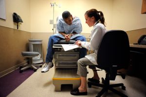 042810_HOSPITAL_CFW- Medicaid patient, Thomas Crippen looks over paperwork after being treated by Family Nurse Practitioner, Amy Quinone at Denver Health's Adult Urgent Care Clinic. Colorado can afford to add about 67,500 people to Medicaid and other gove