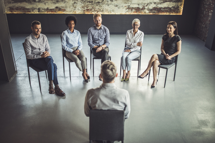 Group of business people listening to their coach during a group therapy.
