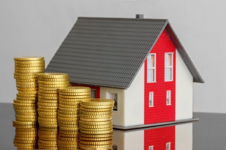 Ascending stacks of coins next to a model home