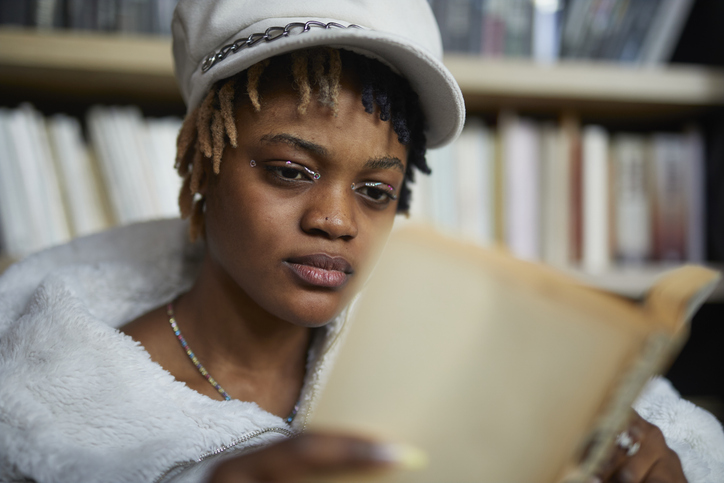 young African descent lady reading book at cafe