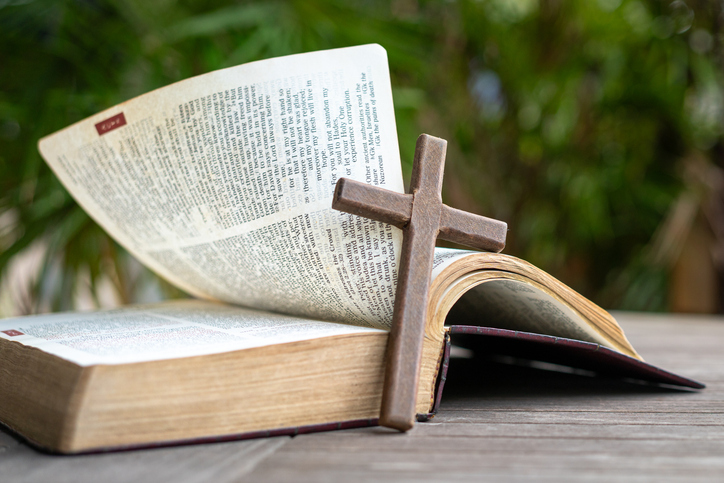 Wooden crucifix cross next to Holy Bible.